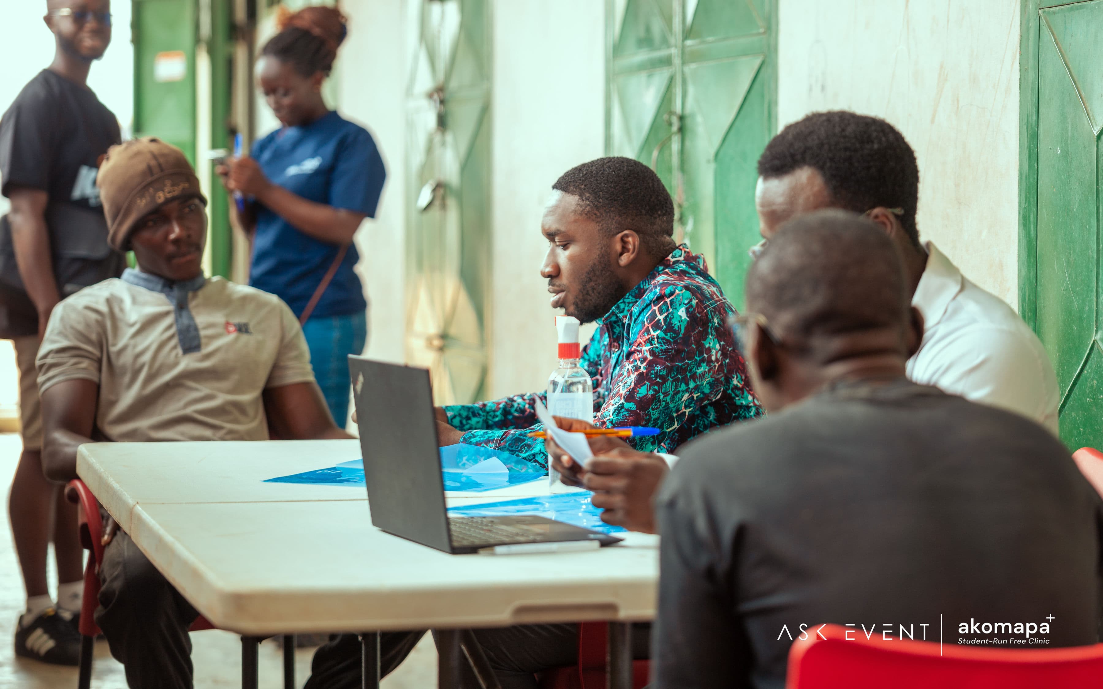 Akomapa volunteer conducting patient intake with a laptop at a community clinic